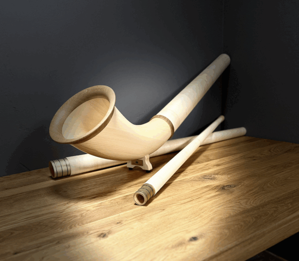 Hochwertiges Alphorn mit Holzmundstück, elegant auf einem Holztisch präsentiert, ideal für traditionelle Klangerlebnisse.