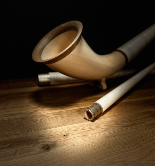 Hochwertiges hölzernes Alphorn mit präzise gearbeiteten Mundstücken, präsentiert auf einem eleganten Holzuntergrund.
