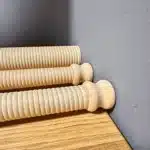 Drei hochwertige Holzmundstücke für Alphörner auf einem Holztisch vor grauer Wand, NATURINSTRUMENTE Heimatklang.