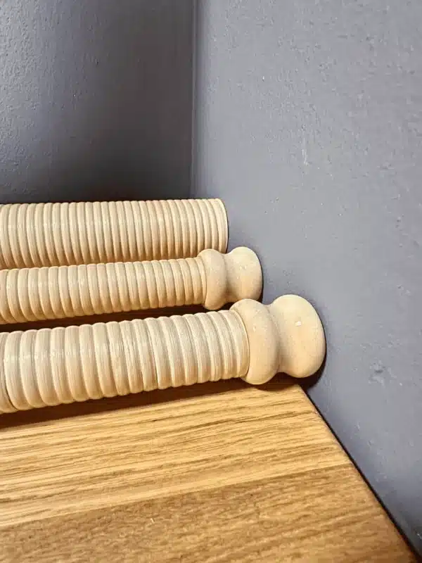 Drei hochwertige Holzmundstücke für Alphörner auf einem Holztisch vor grauer Wand, NATURINSTRUMENTE Heimatklang.