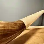 Hochwertige Alphörner aus Holz, kombiniert mit präzise gefertigten Mundstücken, auf einem Holztisch vor blauer Wand.