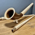 Alpenhorn aus edlem Holz auf Holztisch dargestellt, mit Details der feinen Struktur, für Naturinstrumente-Enthusiasten.