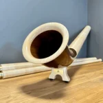 Alphorn aus hochwertigem Holz mit elegantem Mundstück auf Holztisch, präsentiert von NATURINSTRUMENTE Heimatklang.