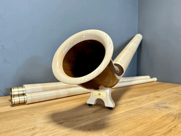 Alphorn aus hochwertigem Holz mit elegantem Mundstück auf Holztisch, präsentiert von NATURINSTRUMENTE Heimatklang.