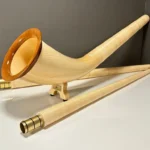 Alpenhorn in edlem Holzdesign mit passenden Mundstücken, präsentiert auf einem Tisch, betont Handwerkskunst und Klangqualität.