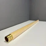 Hochwertiges Alphorn-Holzmundstück auf weißem Tisch vor grauer Wand. Perfekt für NATURINSTRUMENTE Heimatklang.