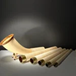 Set alpiner Alphorn-Segmente und Holzmundstück auf Tisch, beleuchtet, symbolisiert handwerkliche Qualität und Naturklang.