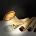 Alpenhorn mit edlem Holzmundstück, präsentiert auf einem Tisch. Perfekt für Naturinstrumente-Enthusiasten und Heimatklang-Liebhaber.