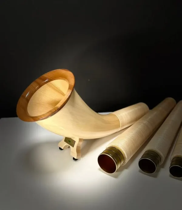 Alpenhorn mit edlem Holzmundstück, präsentiert auf einem Tisch. Perfekt für Naturinstrumente-Enthusiasten und Heimatklang-Liebhaber.