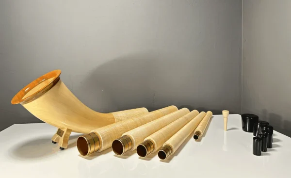 Alphorn in Einzelteilen mit dazugehörigen Holzmundstücken auf einem Tisch, bereit für den Zusammenbau, Heimatklang NATURINSTRUMENTE.