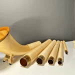 Alphorn aus hellem Holz mit Mundstücken, zerlegt, auf weißem Tisch präsentiert. Hochwertige Handwerkskunst von NATURINSTRUMENTE Heimatklang.