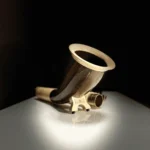 Elegantes Alphorn-Mundstück aus Holz auf glänzendem Tisch, Fokus auf Handwerkskunst und natürliche Materialien von Heimatklang.