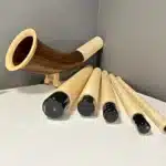 Modulares Alphorn aus Holz mit separaten, hochwertigen Holzmundstücken auf einem Tisch ausgestellt.