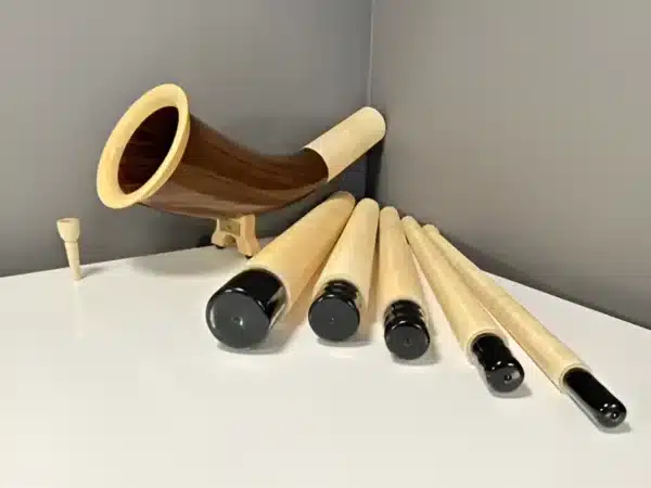 Modulares Alphorn aus Holz mit separaten, hochwertigen Holzmundstücken auf einem Tisch ausgestellt.