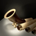 Alphorn und Holzmundstücke auf dunklem Hintergrund, präsentieren hochwertige Handwerkskunst von NATURINSTRUMENTE Heimatklang.