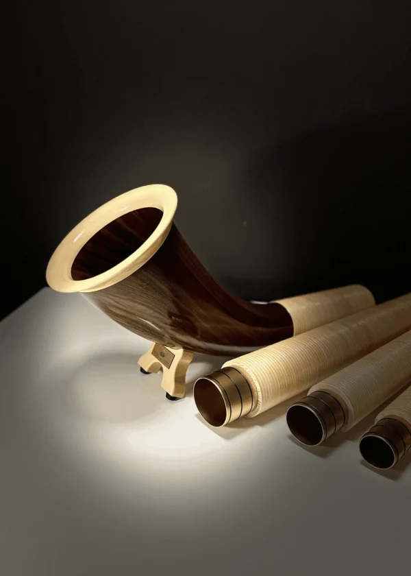 Alphorn und Holzmundstücke auf dunklem Hintergrund, präsentieren hochwertige Handwerkskunst von NATURINSTRUMENTE Heimatklang.