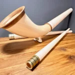 Handgefertigte Alphörner mit edlen Holzmundstücken auf Holztisch, ideal für authentische Heimatklänge von NATURINSTRUMENTE.