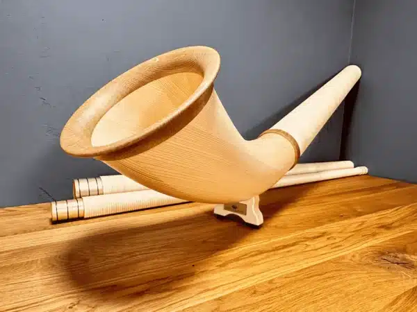 Hochwertiges Alphorn mit sorgfältig verarbeitetem Holzmundstück auf Holztisch, präsentiert von NATURINSTRUMENTE Heimatklang.