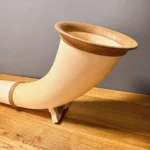 Elegantes Alphorn mit Holzmundstück auf einem Tisch, perfekt für den authentischen Heimatklang mit Naturinstrumenten.