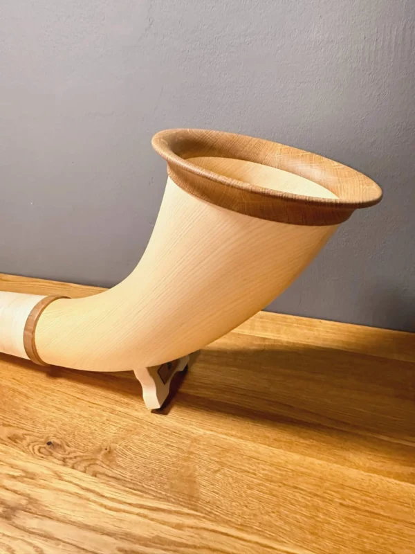 Elegantes Alphorn mit Holzmundstück auf einem Tisch, perfekt für den authentischen Heimatklang mit Naturinstrumenten.