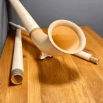 Alphorn und Holzmundstücke auf Holztisch zeigen traditionelle Handwerkskunst von NATURINSTRUMENTE Heimatklang.