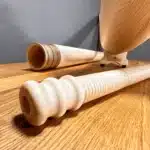 Alphorn und zwei präzise gefertigte Holzmundstücke auf Holzuntergrund, Fokus auf handwerkliche Qualität von Naturinstrumenten.