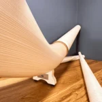 Alphörner aus hellem Holz auf Holzoberfläche, Perspektive von unten. Hochwertige Blasinstrumente für authentischen Heimatklang.