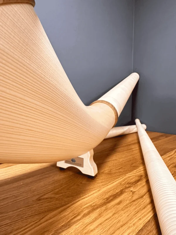 Alphörner aus hellem Holz auf Holzoberfläche, Perspektive von unten. Hochwertige Blasinstrumente für authentischen Heimatklang.