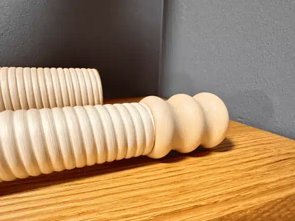 Handgefertigte, geriffelte Holzmundstücke für Alphörner liegen auf einem Holztisch, ideal für Heimatklang-Enthusiasten.