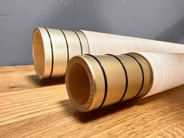 Detailaufnahme von zwei hochwertigen Alphorn-Mundstücken aus Holz, edel verarbeitet, auf Holztisch liegend.
