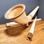 Hochwertige Alphörner mit Holzmundstücken auf Holztisch im Detail, präsentiert von NATURINSTRUMENTE Heimatklang.