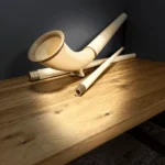 Hochwertiges Alphorn auf Holztisch, zeigt die feine Handwerkskunst von NATURINSTRUMENTE für authentischen Heimatklang.
