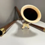 Alphorn aus edlem Holz mit detailreichen Mundstücken, präsentiert auf weißem Hintergrund. Hochwertige Handwerkskunst.