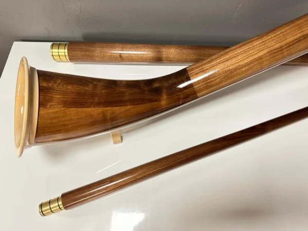 Alpenhorn aus edlem Holz mit hochwertigen Mundstücken, präsentiert auf weißem Untergrund, ideal für NATURINSTRUMENTE Heimatklang.