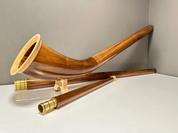 Alphorn aus edlem Holz mit präzisen Mundstücken, präsentiert auf einer glatten Oberfläche, ideal für NATURINSTRUMENTE Heimatklang.