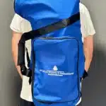 Person trägt eine große blaue Tasche mit Logo NATURINSTRUMENTE Heimatklang für Alphörner und Zubehör.