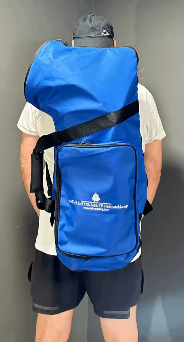 Person trägt eine große blaue Tasche mit Logo NATURINSTRUMENTE Heimatklang für Alphörner und Zubehör.