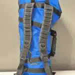 Blauer Rucksack mit schwarzen Trägern an der Wand hängend, ideal für den Transport von Naturinstrumenten wie Alphörnern.