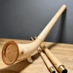 Alphorn aus hellem Holz auf Holztisch, mit separaten Rohrstücken für vielfältige Naturklänge bei Heimatklang.