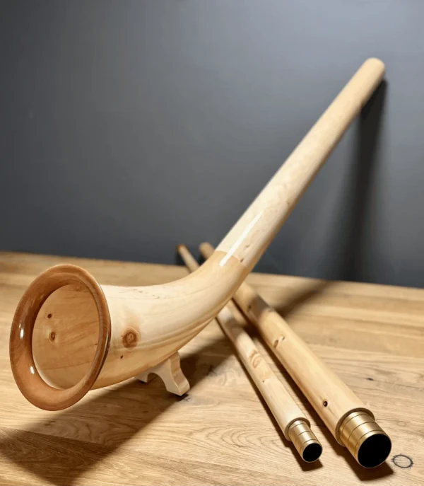 Alphorn aus hellem Holz auf Holztisch, mit separaten Rohrstücken für vielfältige Naturklänge bei Heimatklang.