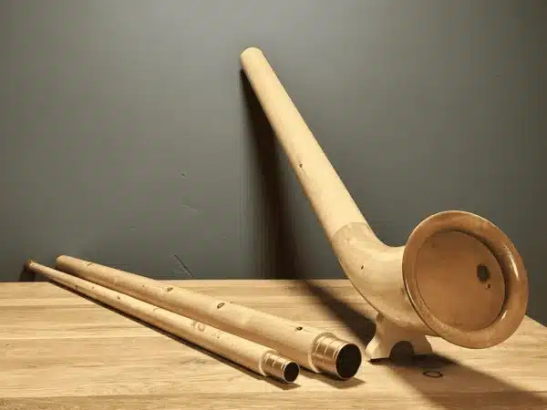 Alphorn aus Holz und passende Mundstücke auf Holztisch, präsentiert von NATURINSTRUMENTE Heimatklang.