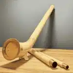 Alphorn aus Holz, detailreich gestaltet, mit hochwertigem Mundstück auf Holztisch präsentiert. Ideal für Naturinstrumente-Liebhaber.