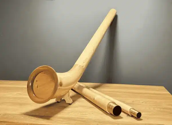Alphorn aus Holz, detailreich gestaltet, mit hochwertigem Mundstück auf Holztisch präsentiert. Ideal für Naturinstrumente-Liebhaber.
