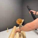 Ein Mann montiert hochwertige Alphornteile und Holzmundstück auf einem Tisch, in einer Werkstatt für Naturinstrumente.