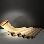 Alpenhorn und Mundstück aus Holz vor dunklem Hintergrund, präsentiert als hochwertige Naturinstrumente von Heimatklang.
