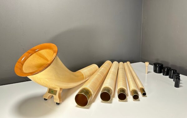 Alphorn aus Holz in Einzelteilen, inklusive Mundstück, auf einem Tisch präsentiert. Ideal für NATURINSTRUMENTE Heimatklang.