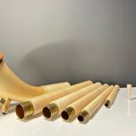 Alpenhorn und Holzmundstück-Set auf weißem Tisch, präsentiert von NATURINSTRUMENTE Heimatklang für höchsten Klanggenuss.