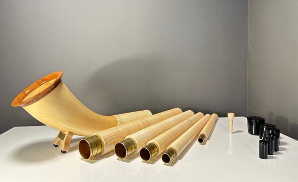Alpenhorn und Holzmundstück-Set auf weißem Tisch, präsentiert von NATURINSTRUMENTE Heimatklang für höchsten Klanggenuss.