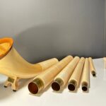 Alpenhorn mit Holzmundstück und Einzelteile auf weißem Hintergrund, präsentiert von NATURINSTRUMENTE Heimatklang.