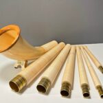 Set von Alphörnern mit hochwertigen Holzmundstücken auf weißem Tisch präsentiert. Perfekt für authentischen Alpenklang.